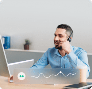 Image of Smiling man with headset uses Irish recruitment phone system at desk, computer monitor and audio waveform visible.