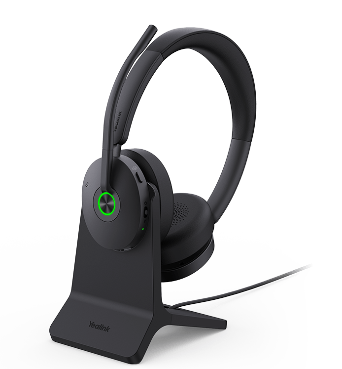 Yealink BH74 headset on a charging stand next to a laptop with the BT51-C USB dongle